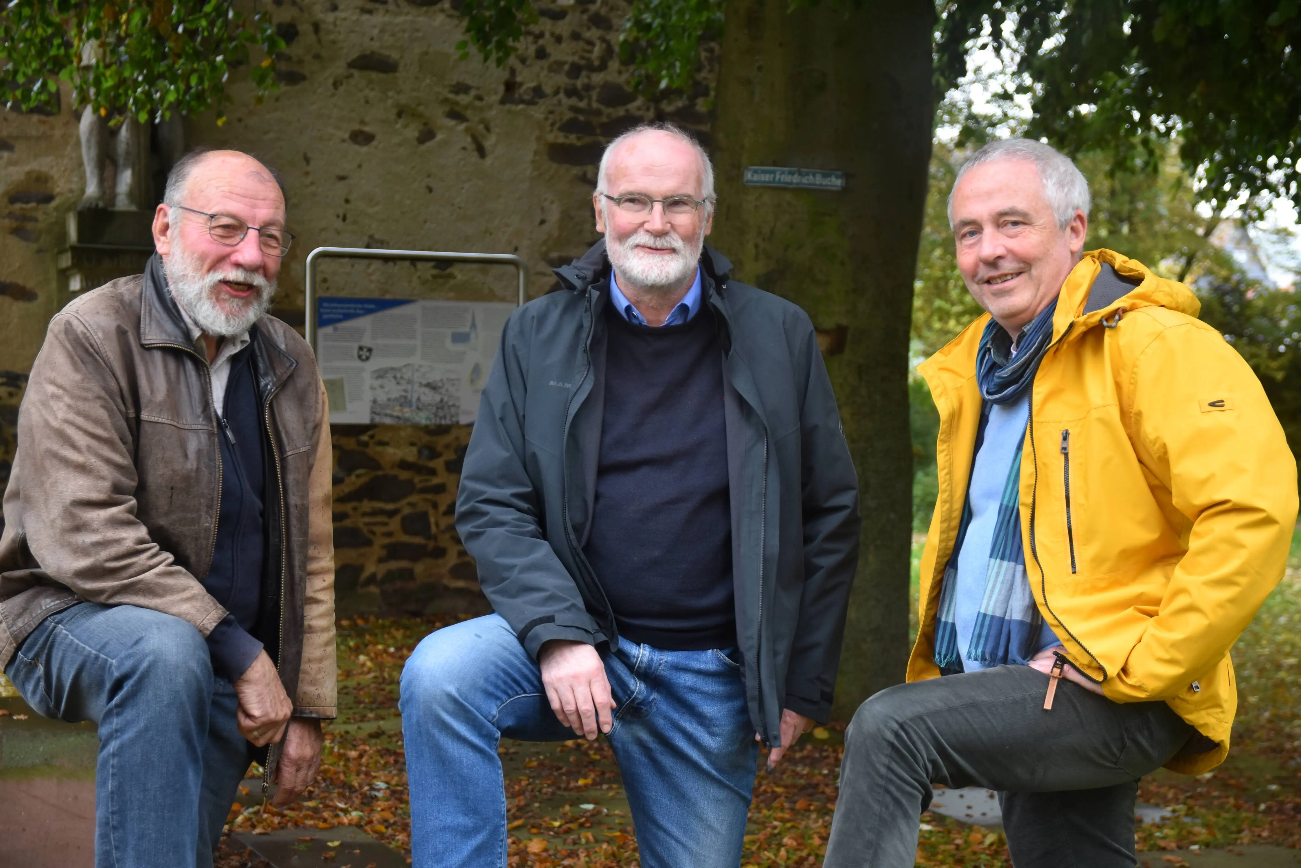 Konrad Schulz, Rainer Böhm und Hans Hamrich in Anoraks bzw. Lederjacke stehen vor dem Johanniterturm in Nidda. Jeder hat ein Bein auf ein Podest gestellt. Sie blicken in die Kamera