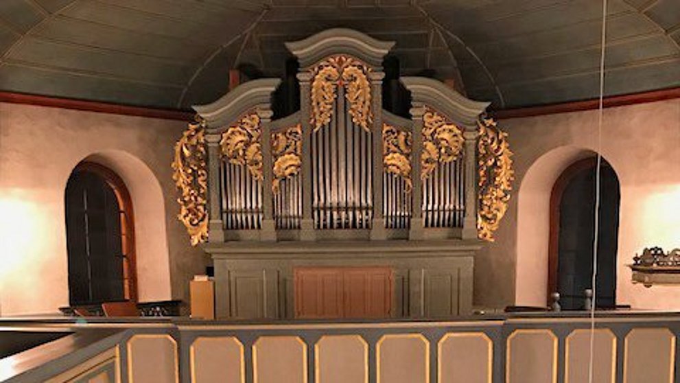 Blick während eines Konzertes in der evangelischen Kirche Köppern von der Rückempore über dem Haupteingang auf den Altarraum und Empore mit Orgel darüber. Vor dem Alter sitzt der Künstler mit Akkordeon.