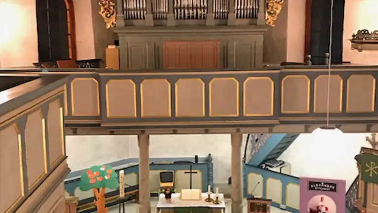 Blick während eines Konzertes in der evangelischen Kirche Köppern von der Rückempore über dem Haupteingang auf den Altarraum und Empore mit Orgel darüber. Vor dem Alter sitzt der Künstler mit Akkordeon.