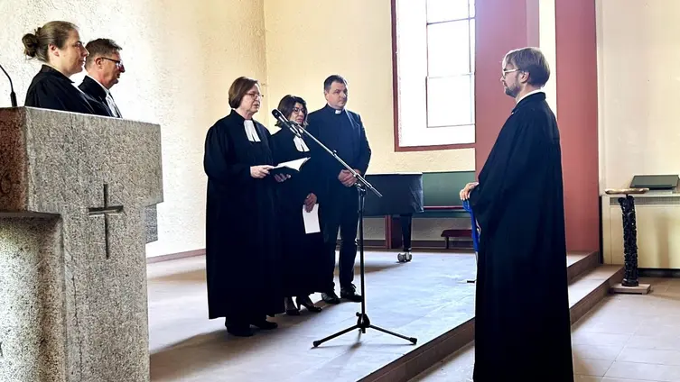 Fünf Personen, davon vier im Talar, stehen auf dem Altar und eine Person steht vor dem Altar mit Blick zu den fünf Personen