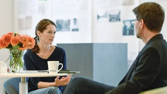 Eine Frau und ein Mann sitzen zusammen am Tisch und unterhalten sich.