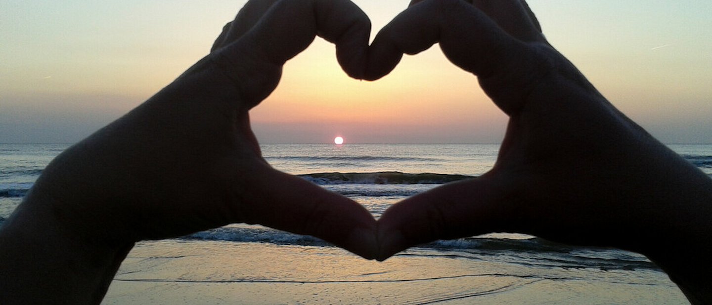Händeherz vor einem Sonnenuntergang