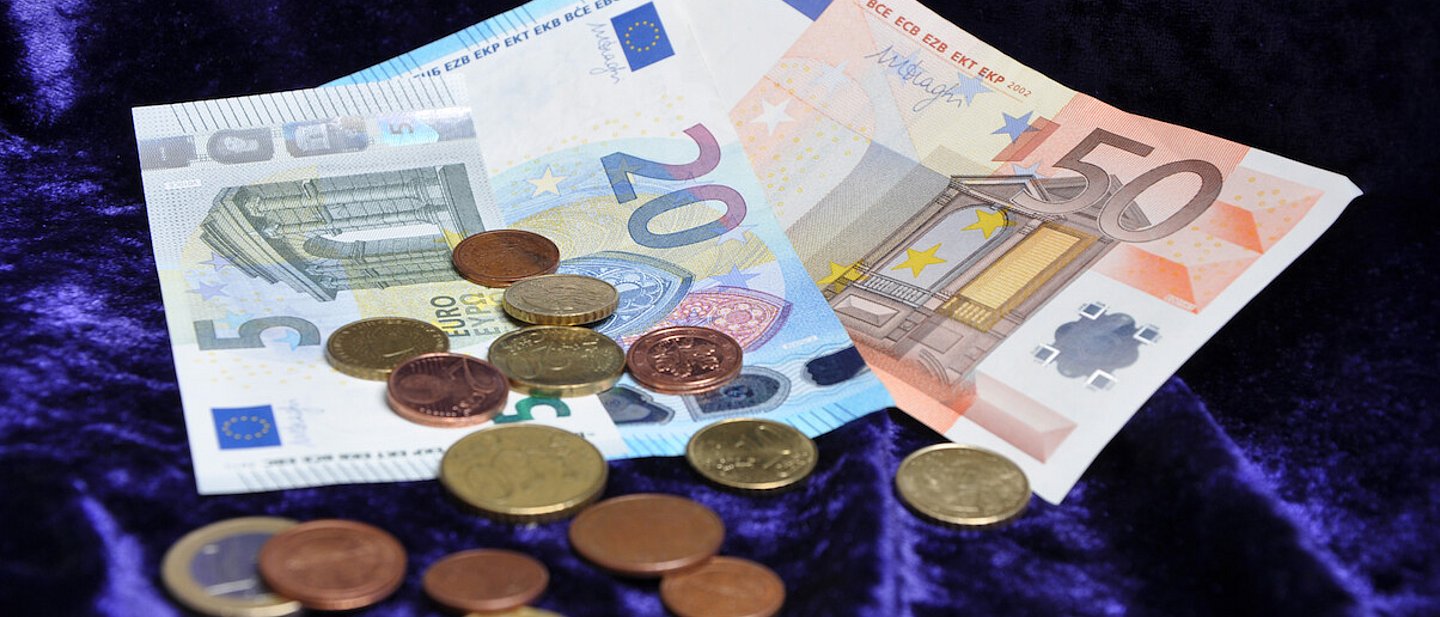 Geldscheine und Münzgeld auf einem lila Samttuch