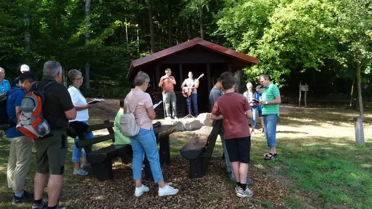 Das Foto zeigte ca. 15 Menschen im Wald, die am Gottesdienst teilnehmen.