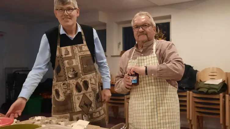 2 Männer mit Schürzen bereiten Essen zu