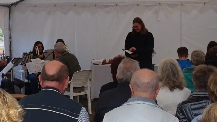 Das Foto zeigt im Zentrum Pfarrerin Christina Meyer, umgeben von mehreren Mitgliedern des Breuberger Posaunenchors und Besuchende des Erntedankgottesdienstes im Festzelt am Kohlplatz in Breuberg-Hainstadt.
