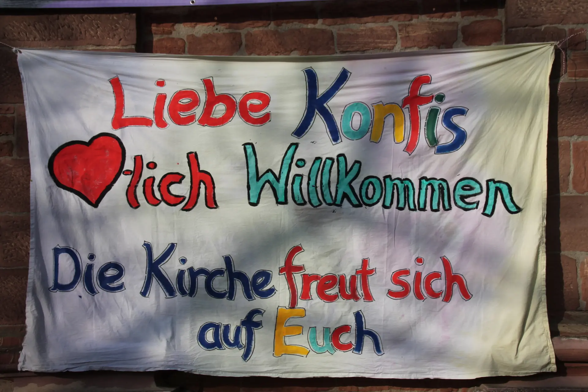 Weißes Tuch bunt bemalt mit einem Willkommensgruß für die Konfis