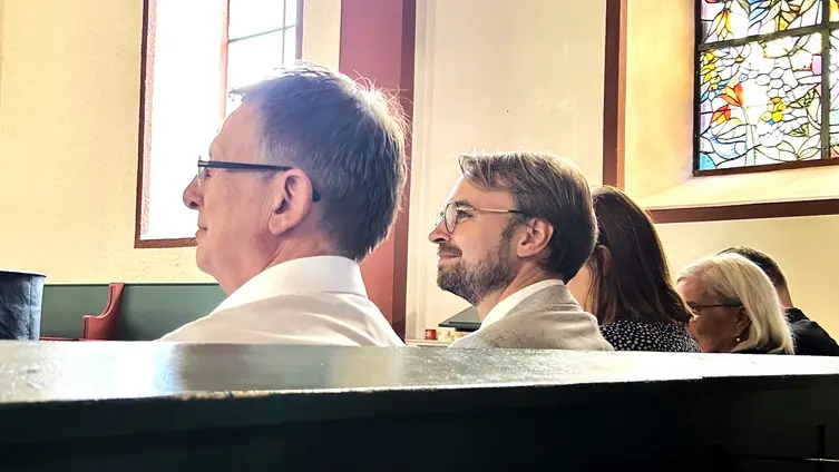 Carsten Tag und Georg Bloch-Jessen sitzen in der Kirchenbank sie sind von hinten fotografiert, so dass man nur das Profil der beiden erkennt