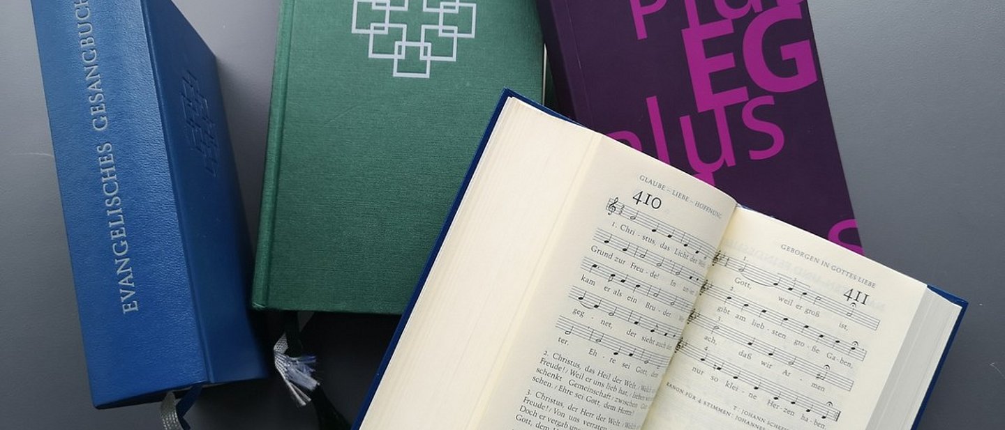Mehrere Ausgaben, ein Gesangbuch ist aufgeschlagen.