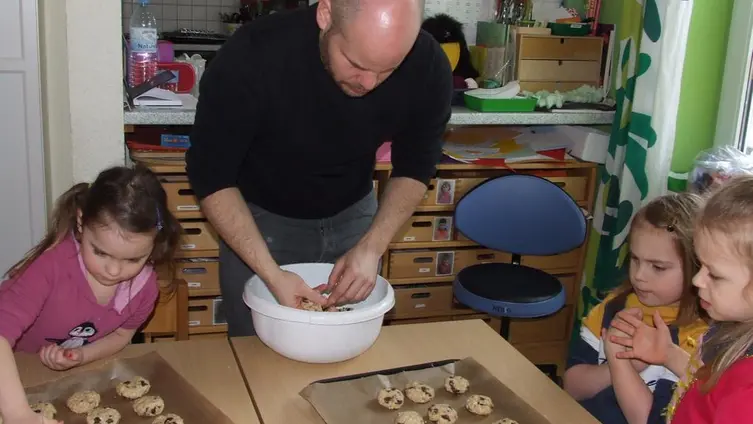 Auf dem Foto sieht man Kinder und Erzieher beim Backen von leckeren gesunden Keksen.
