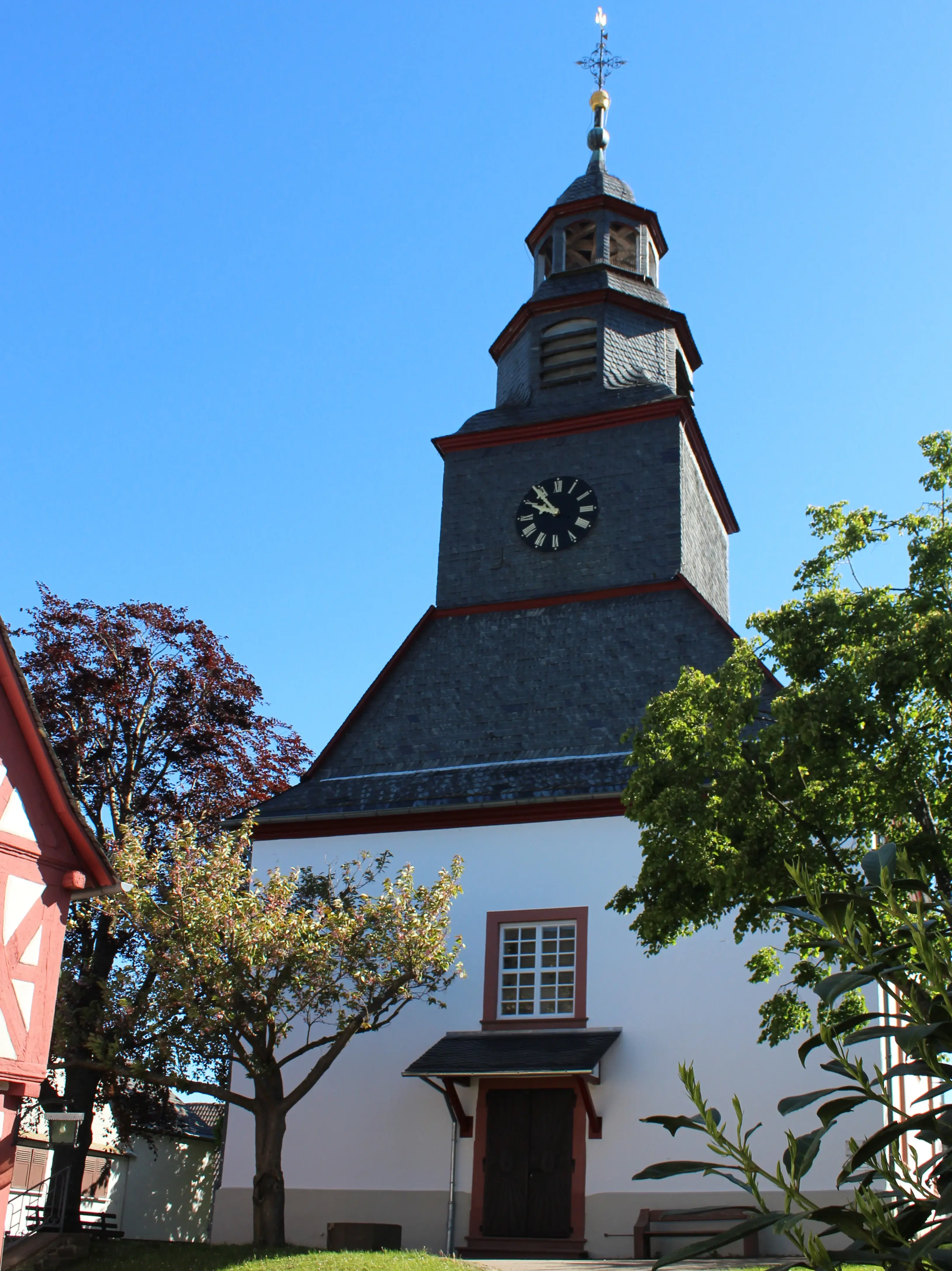 Evangelische Kirche in Merzhausen von der Eingangseite mit Bäumen rechts und links 
