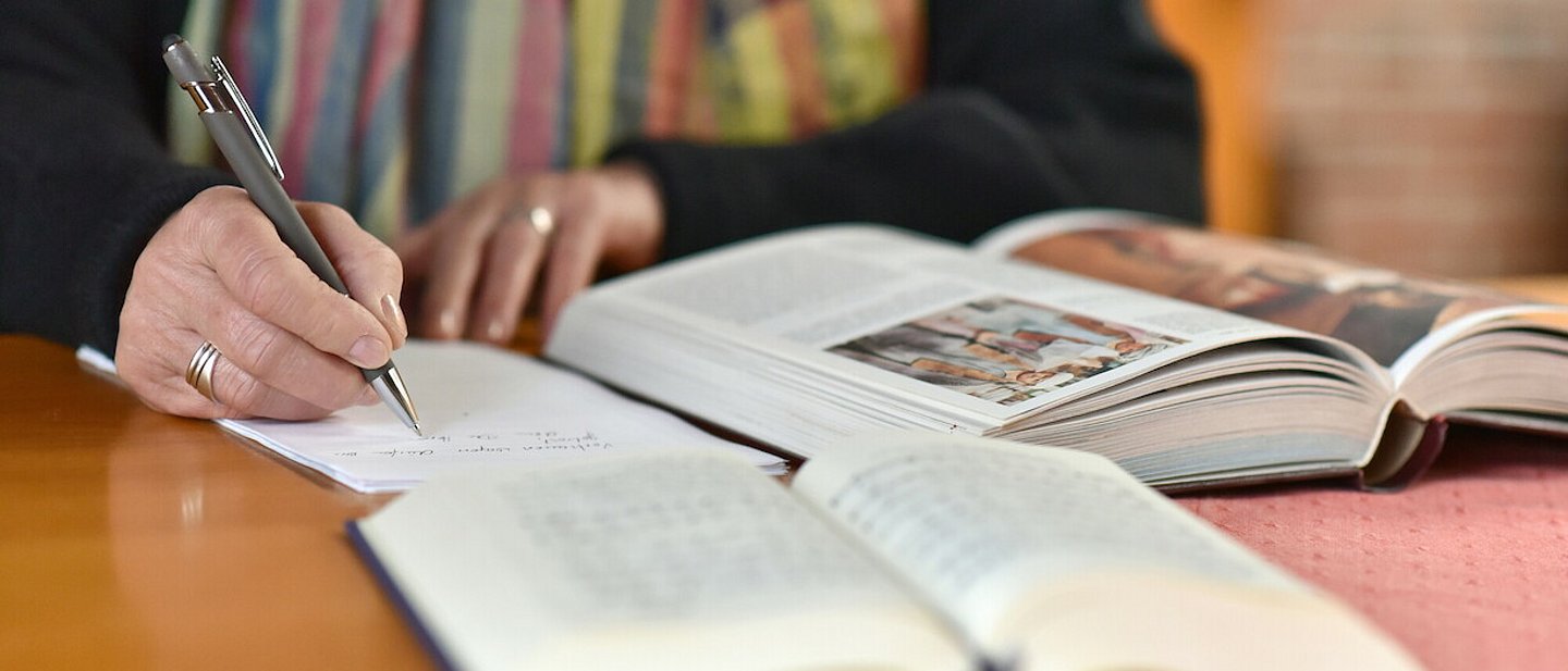 Person arbeitet mit einem Buch und Texten