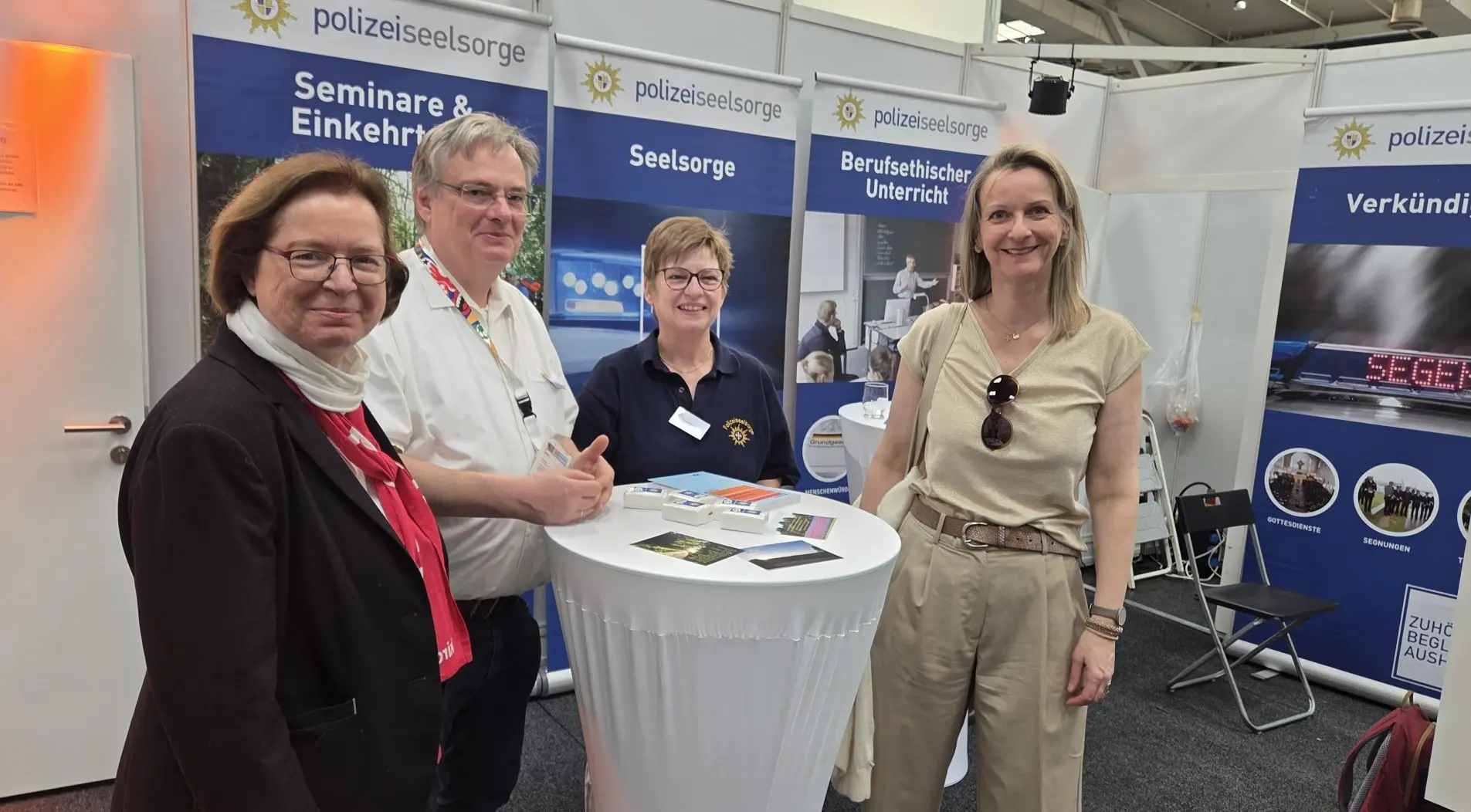 Die vier Personen stehen an einem Stehtisch am Stand der Polizeiseelsorge.