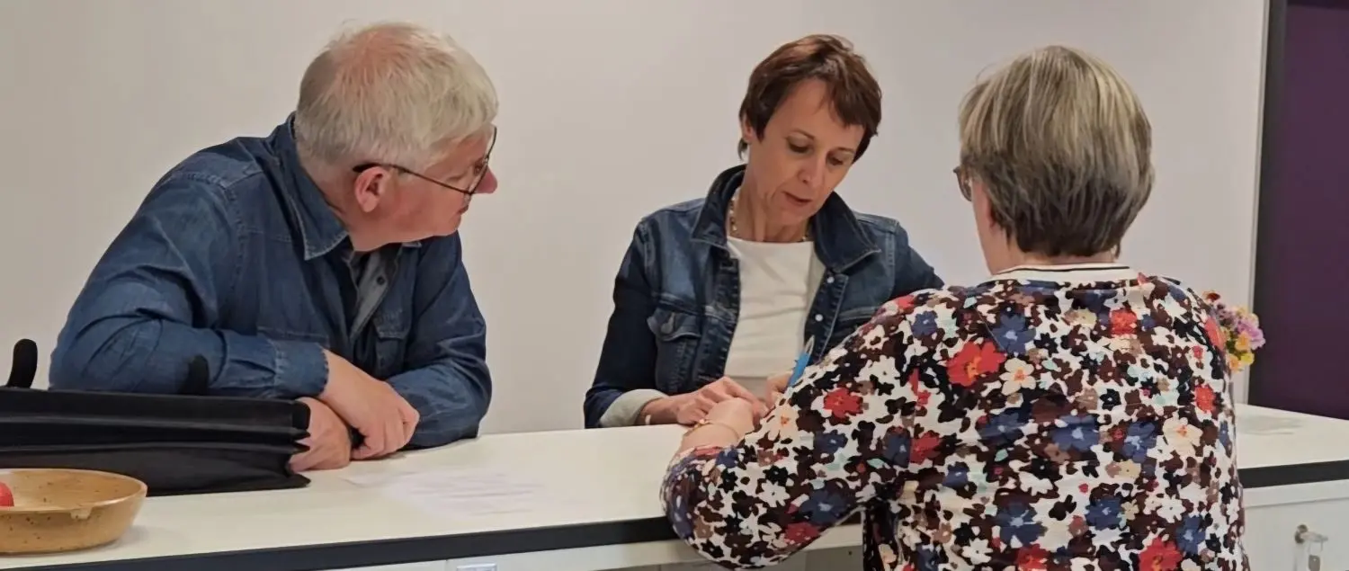 Besprechung im Dekanatsbüro: Zwei Frauen und ein Mann beugen sich an einem Tresen über ein Schriftstück.