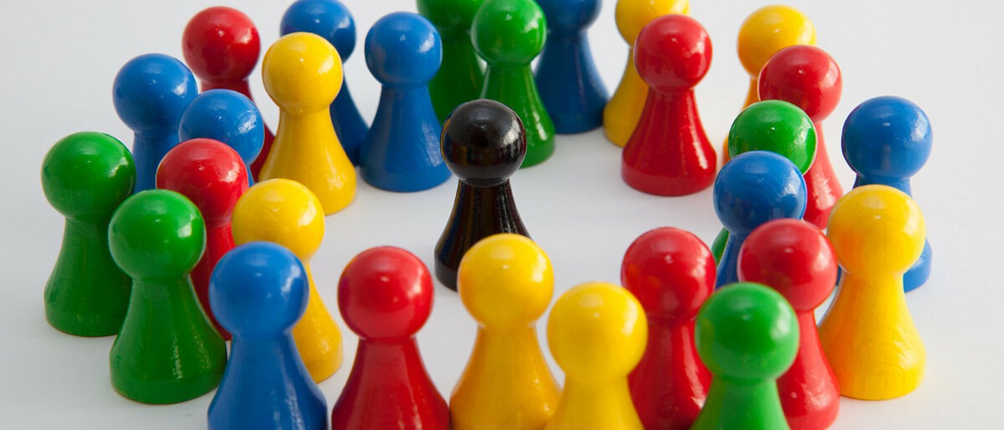 Bunte Spielfiguren umstellen eine schwarze Spielfigur
