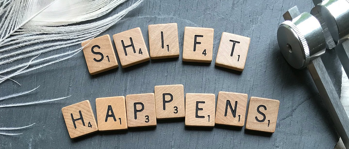 Buchstabenplättchen wie Scrabbel zeigen den Satz "SHIFT HAPPENS"