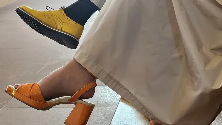 Foto zeigt Beine von Dekanin Hamrich und Dekan Guth, sie trägt orangefarbene Sandalen, er trägt gelbe Budapester Schuhe.