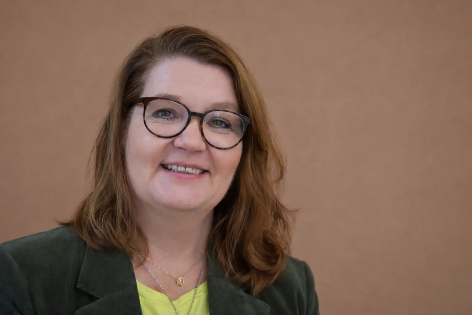 Porträt Astrid Pfarschner, schulterlanges dunkles Haar, Brille, schaut in die Kamera, lächelt freundlich