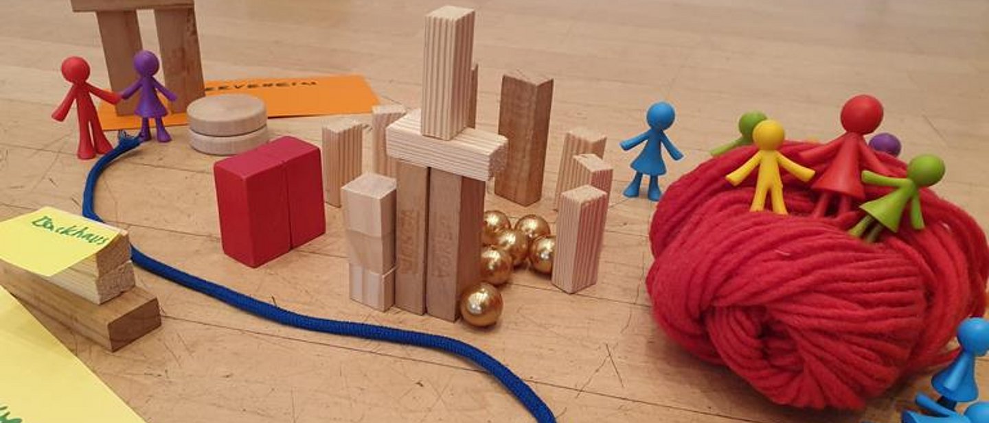 Bauklötzchen, Goldkugeln, bunte Wolle und Plastikfigürchen