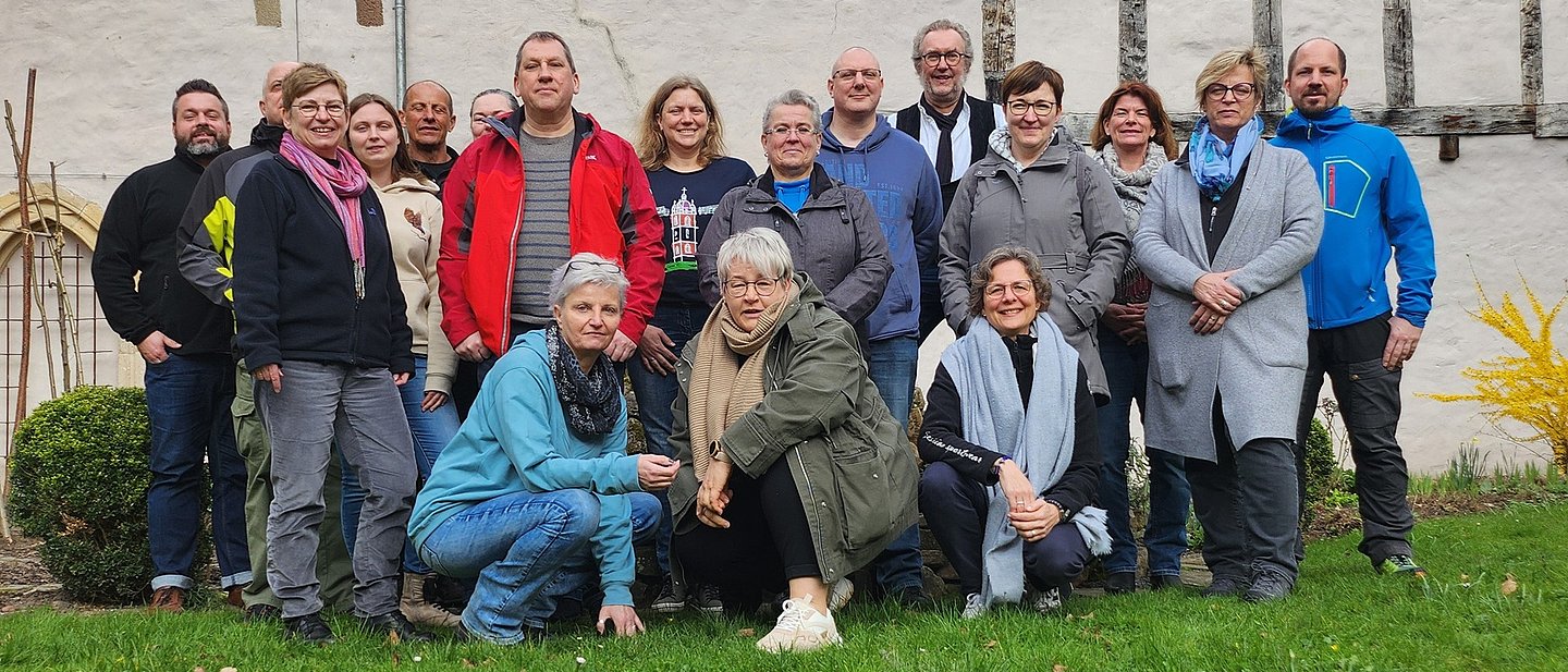 Eine Gruppe von Menschen steht vor einer alten Klostermauer.