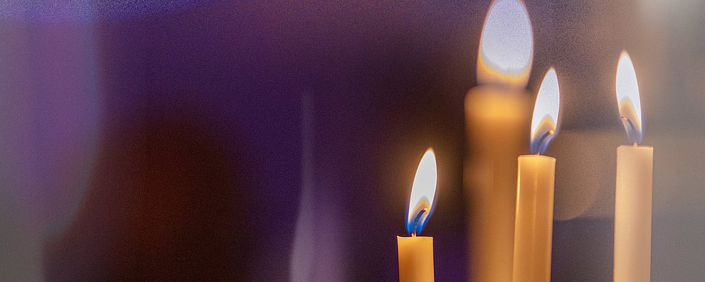 Mehrere Kerzen brennen vor dunklem Hintergrund