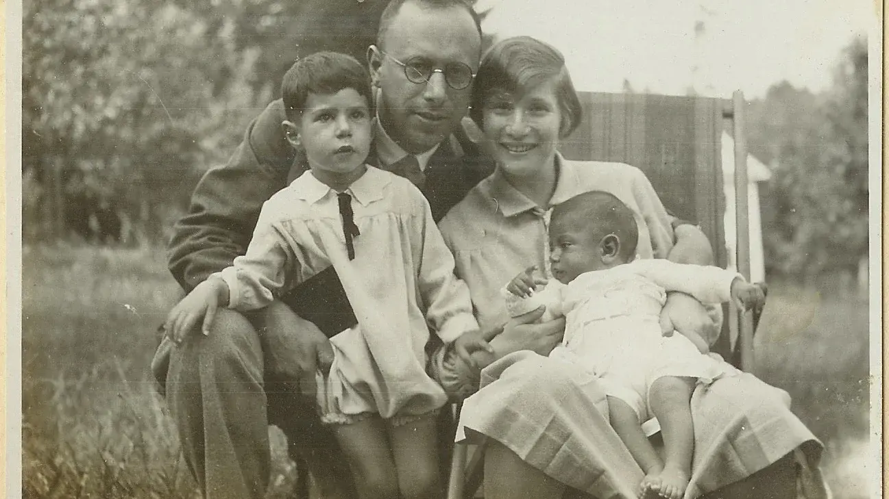 Historisches Bild: ein Elternpaar sitzt Wange an Wange auf einer Wiese. Der Vater hält ein Kind, den Sohn, im Arm, die Mutter ein Baby in einem langen weißen Gewand.