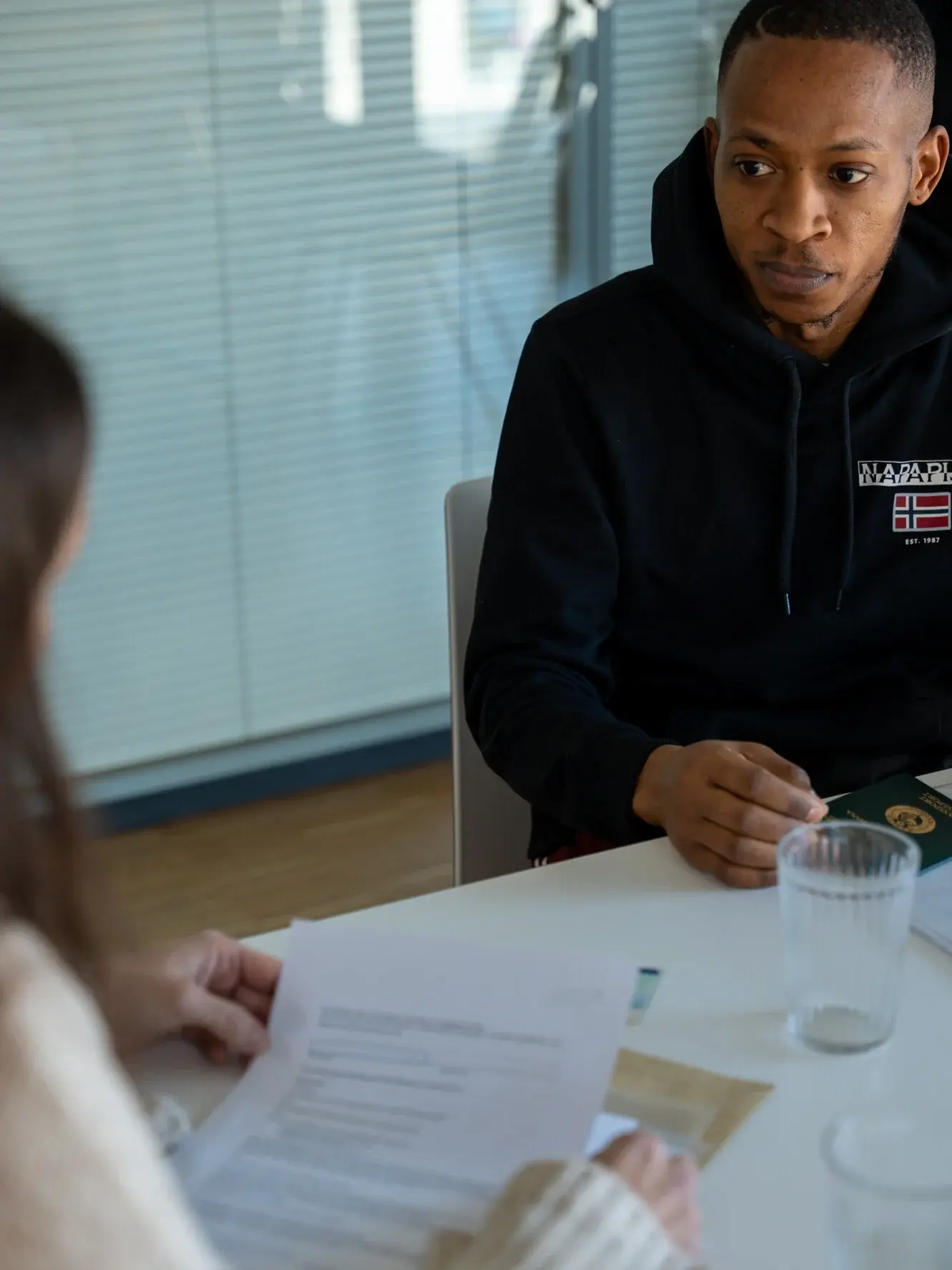 Eine Frau sitzt rechts und berät einen Mann, der ihr links gegenüber an einem Tisch sitzt