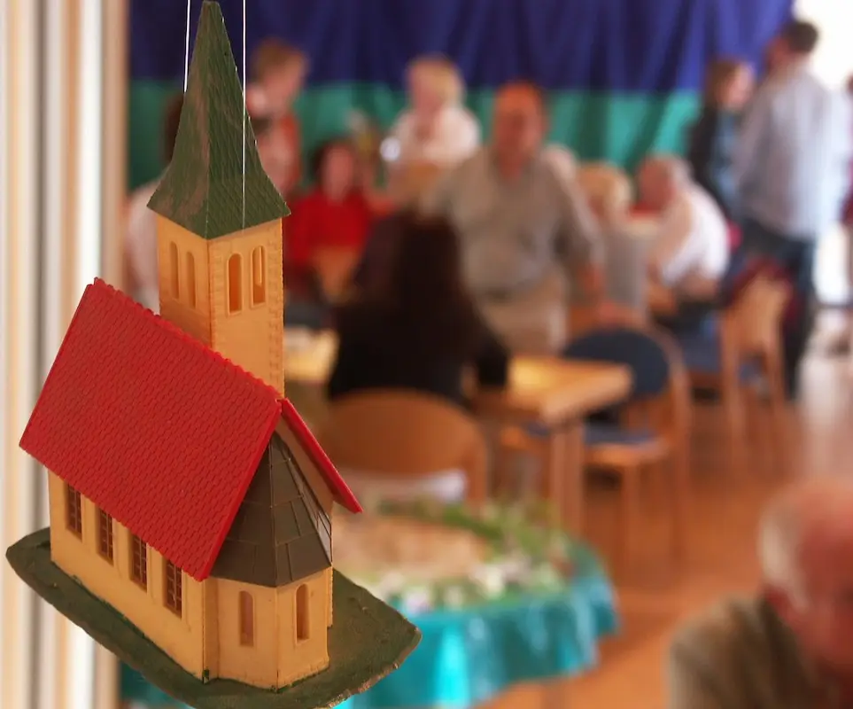 Gemeindearbeit Modell einer Kirche mit Menschen im Hintergrund