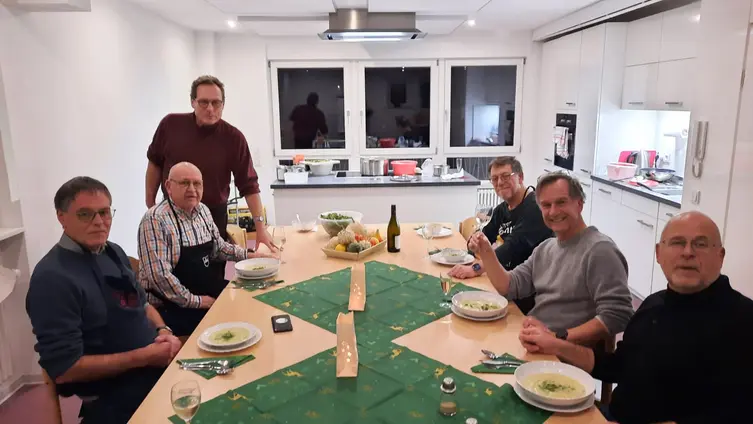 6 Männ der der Kochmützen sitzen um einen Tisch