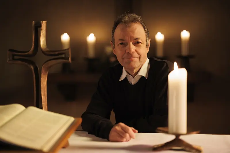 Pfarrer Michael Zopf am Altar mit Bibel, Kreuz und Kerze
