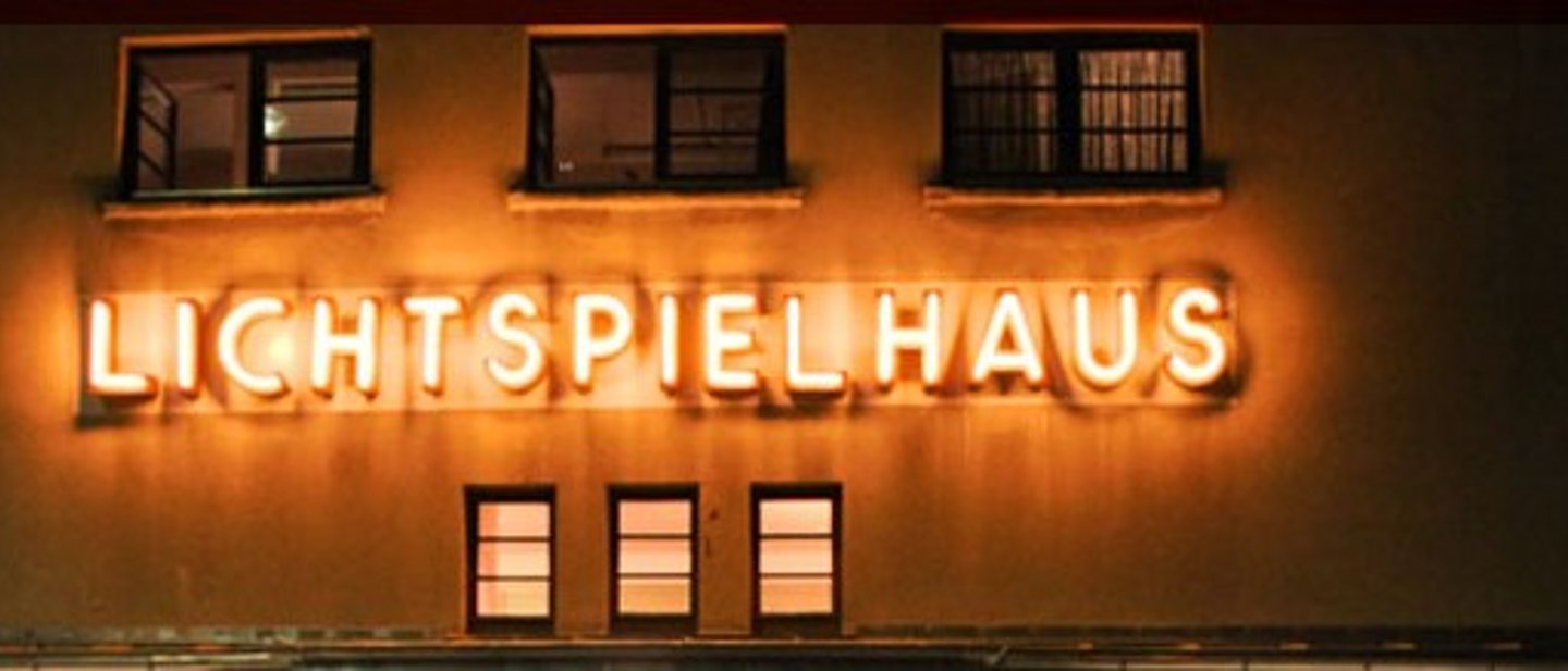 Schriftzug "Lichtspielhaus" leuchtet an einer Wand.