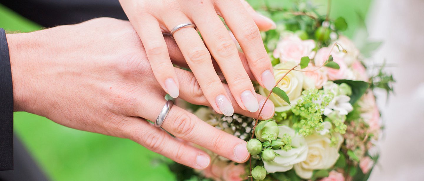 Zwei sich berührende Hände eines Mannes und einer Frau mit Eheringen