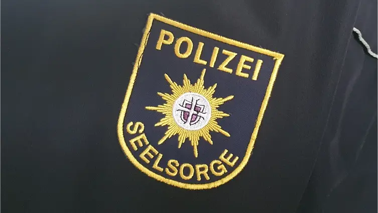 Auf einer blauen Schutzjacke ist das Logo der Polizeiseelsorge aufgenäht.