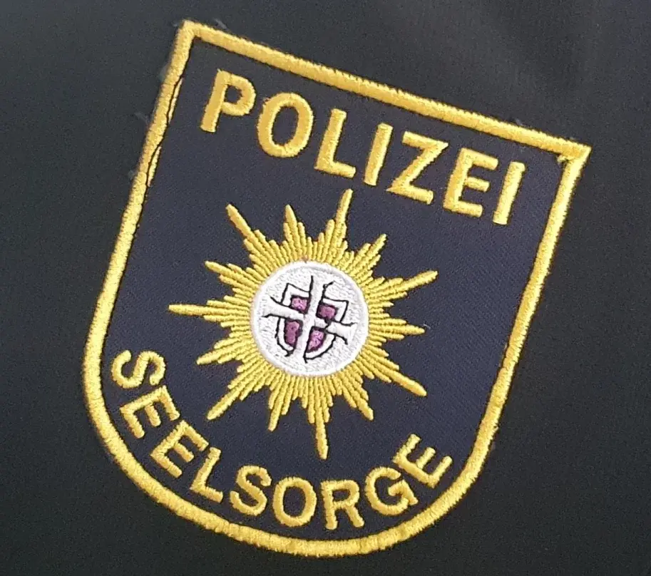 Auf einer blauen Schutzjacke ist das Logo der Polizeiseelsorge aufgenäht.