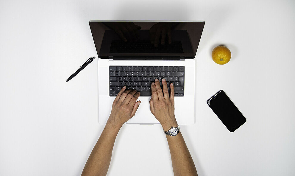 Zwei Hände tippen auf einer Laptop-Tastatur