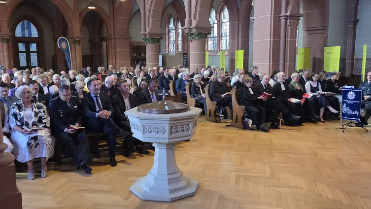 Ein Blick in die Kirche mit vollbesetzten Reihen. Vorne links das Taufbecken.