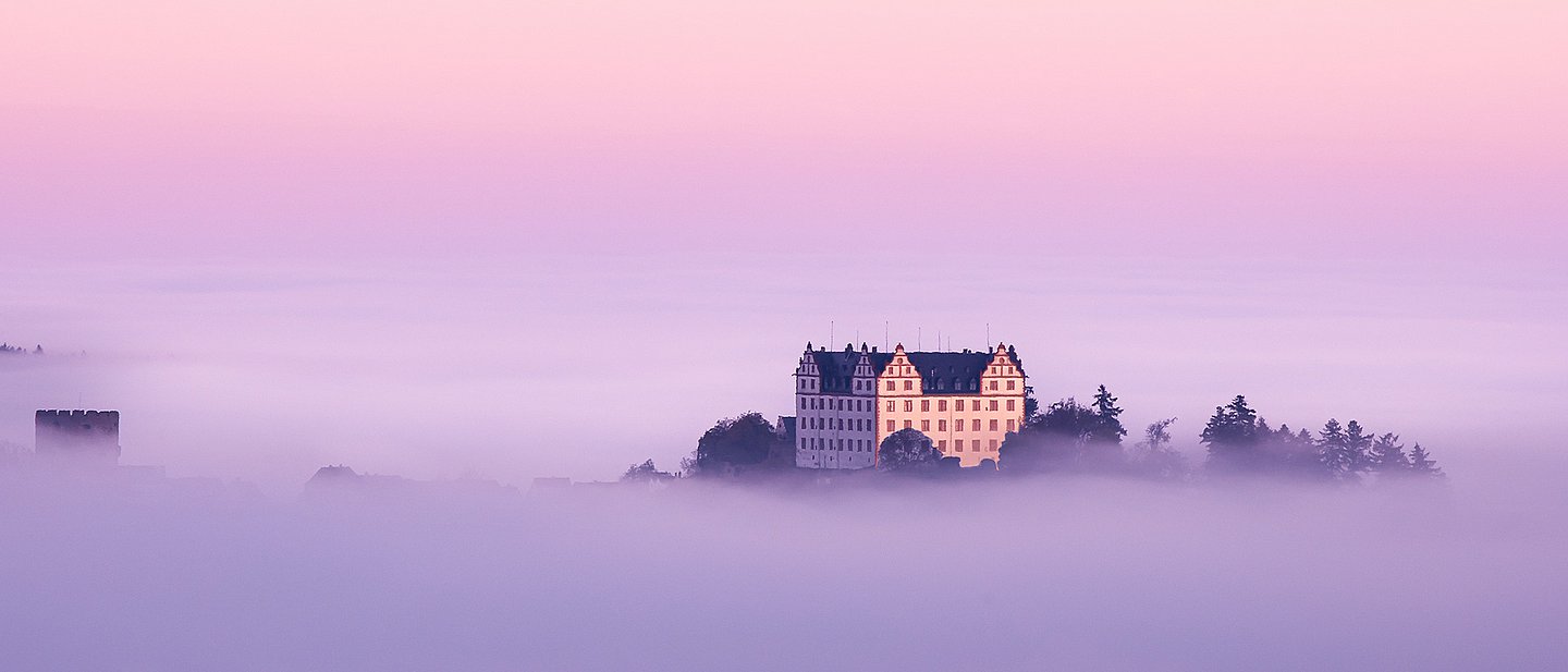 Schloss Lichtenberg im Nebel mit Morgenrot