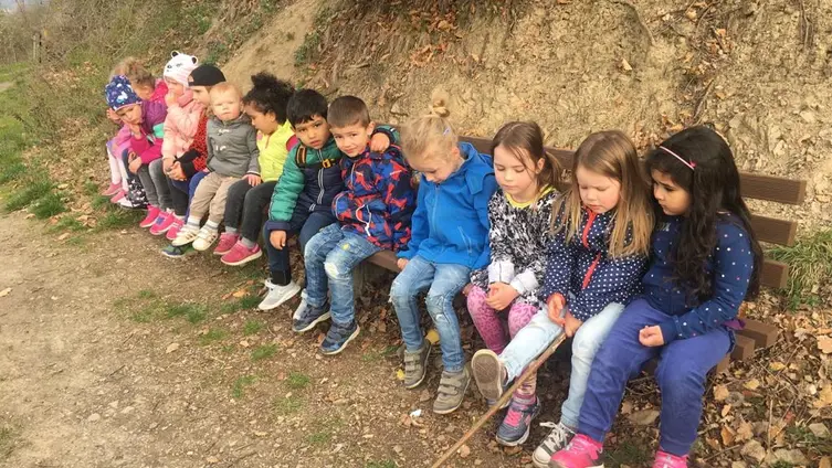 Das Foto zeigt eine Gruppe von KiTakindern auf einer langen Ruhebank.