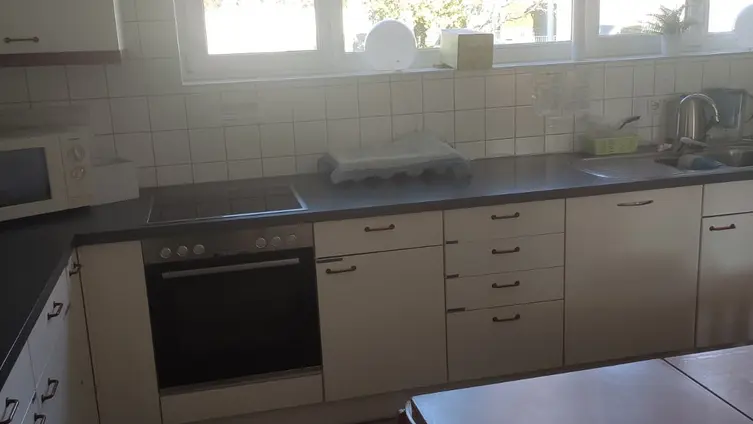 Küche mit Backofen, Herd, Spüle und Spülmaschine sowie Küchenschränken. Auf der Anrichte steht eine Kaffeemaschine.