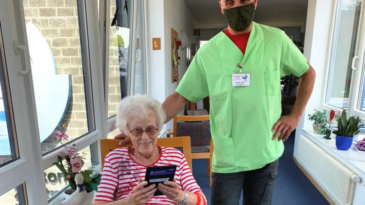 Das Bild zeigt eine ältere Dame mit ihrem Pfleger.