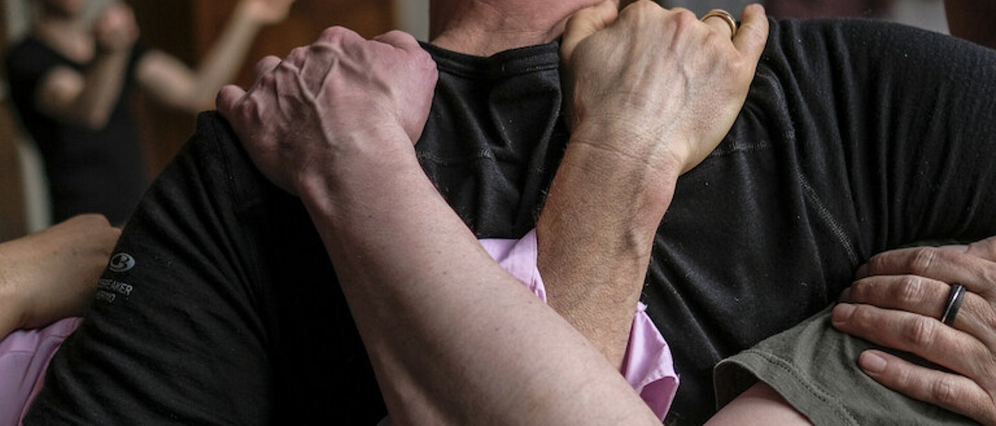 Mehrere Männer stehen Schulter an Schulter und umarmen sich.