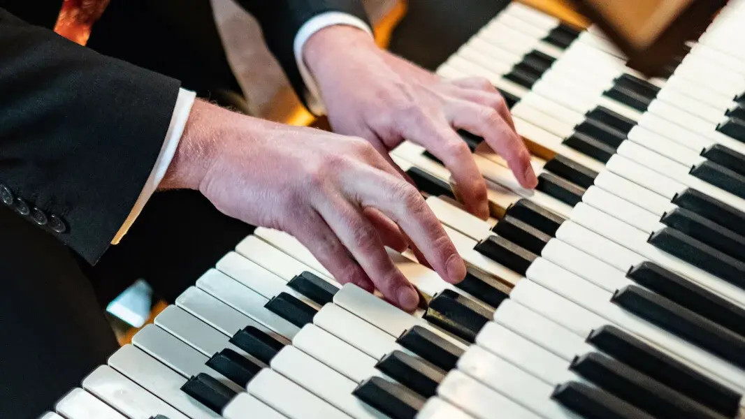 Nahaufnahme der Hände eines Organisten beim Spielen auf einer Orgel.