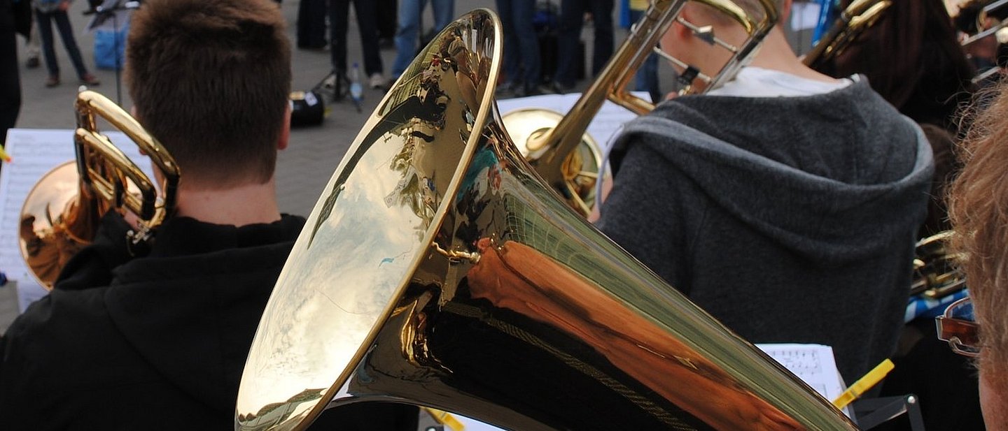 Ein Posaunenchor spielt auf einem Platz in einer Stadt.