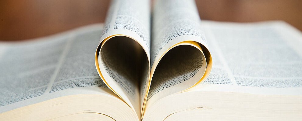 Aufgeschlagene Bibel - Seiten zum Herz gefaltet