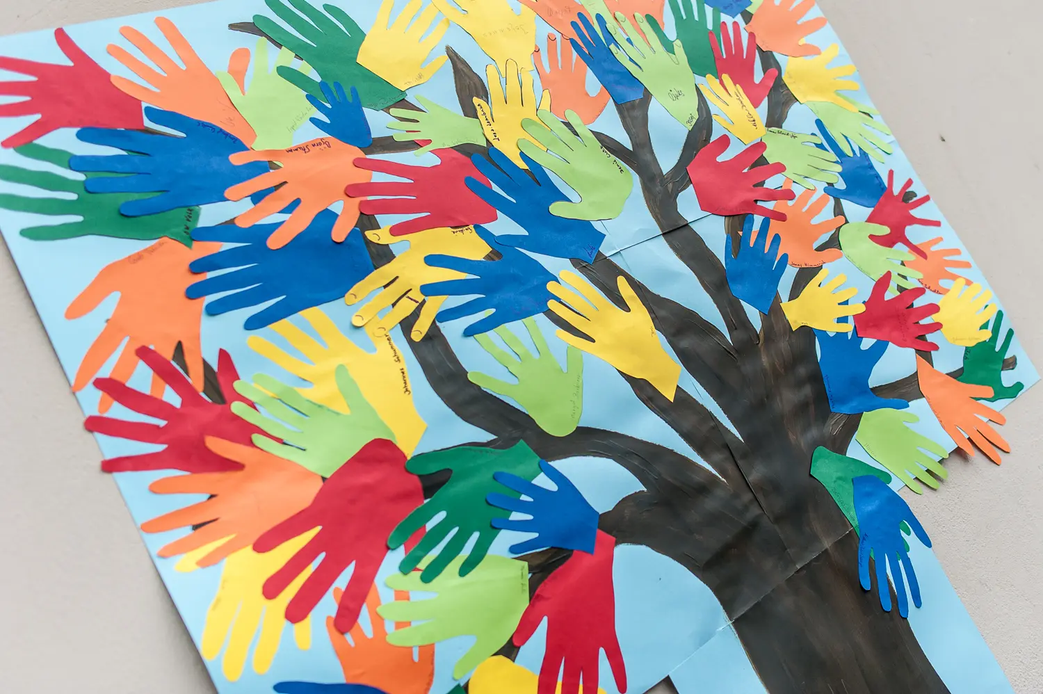 Das Foto zeigt einen aufgemalten Baum mit vielen bunten Handabdrücken als Blätter.