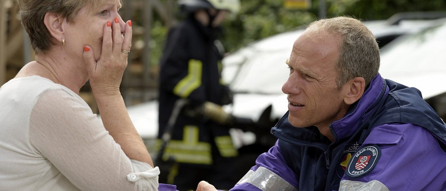 Notfallseelsorger kümmert sich um verzweifelte Frau am Unfallort.