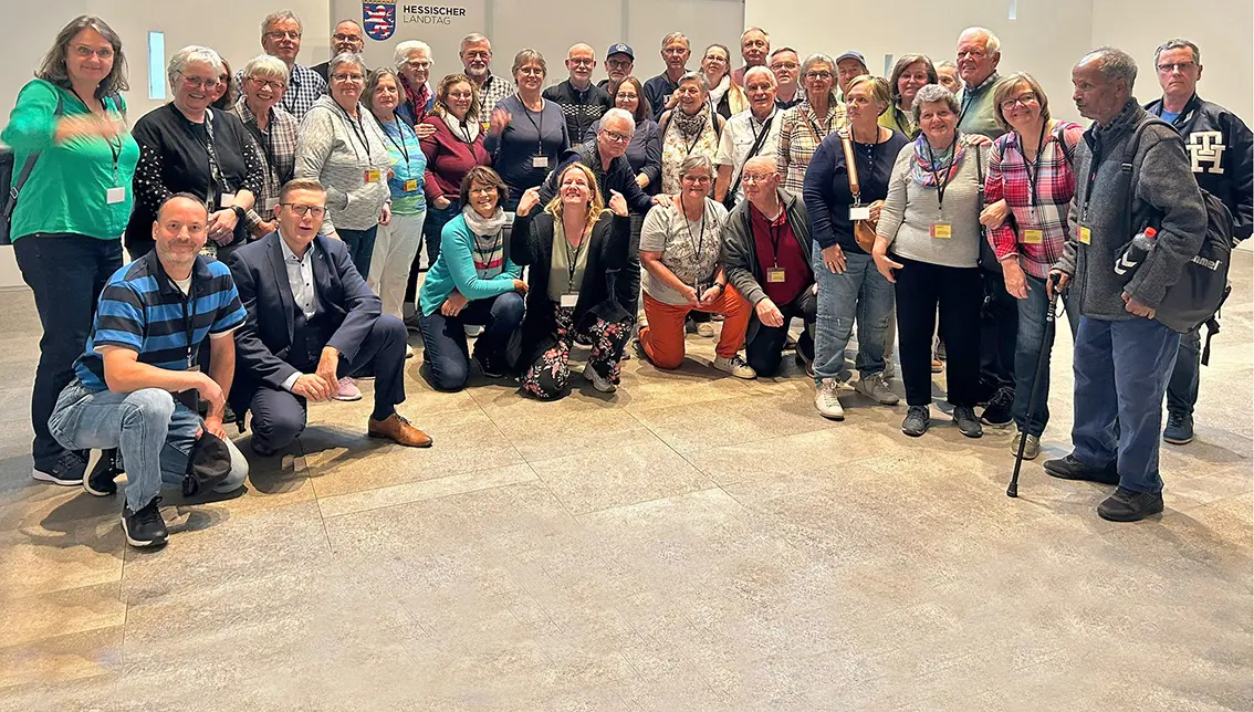 Gruppe von Menschen steht und sitzt für ein gemeinsames Foto im Hessischen Landtag.