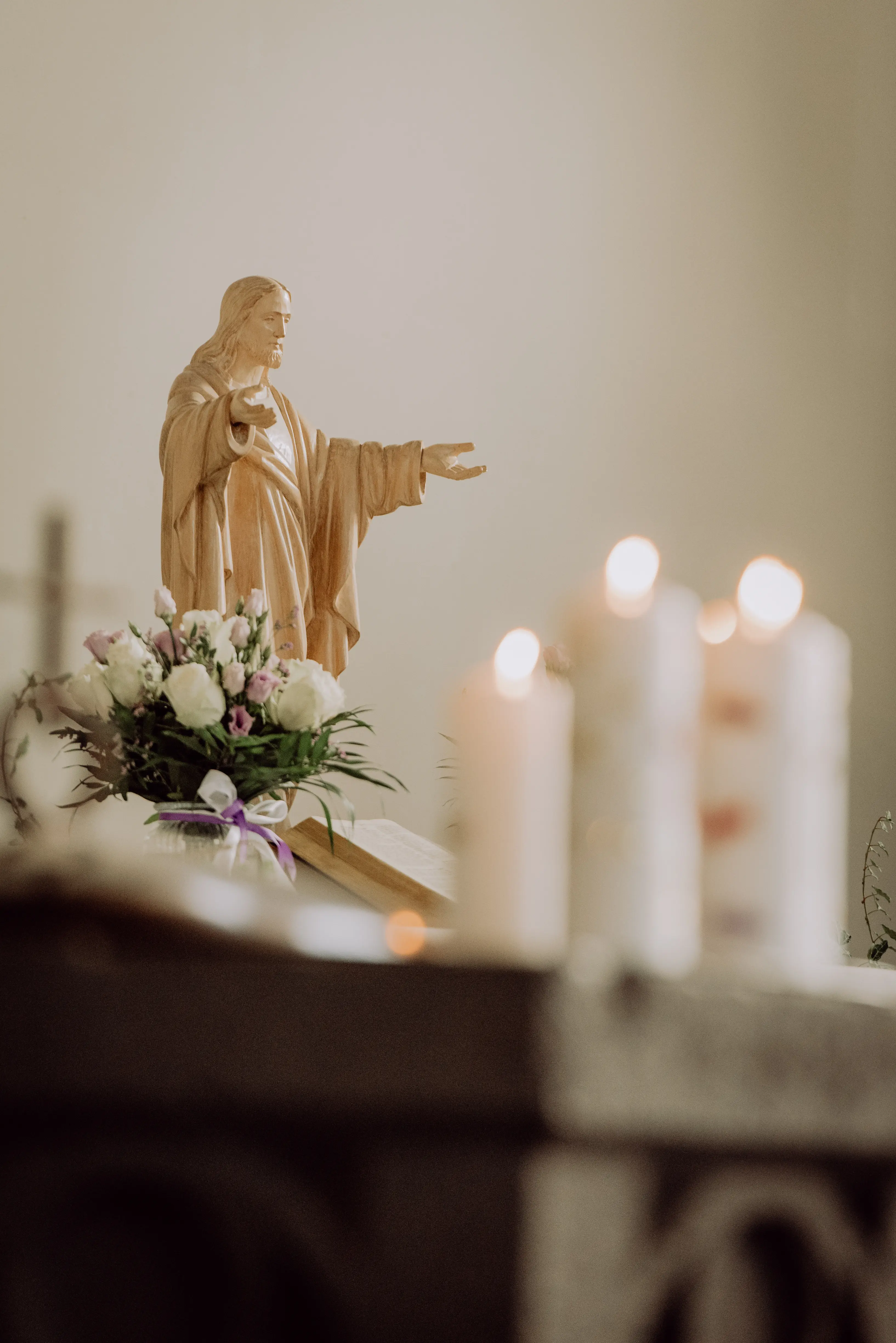 Das Foto zeigt die Christusstatue auf dem Altar in der Markuskirche, im Vordergrund stehen brennende Kerzen.