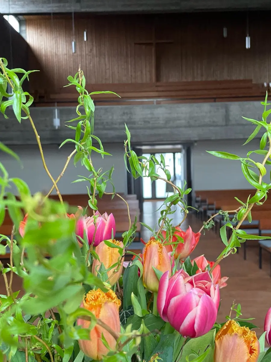 Ein Kirchraum ist durch einen Blumenstrauß hindurch fotografiert.