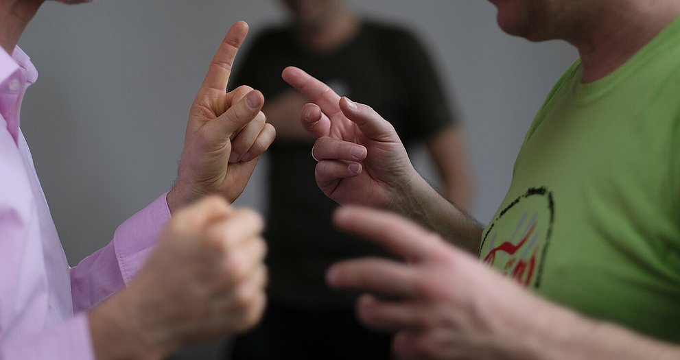 Zwei Männer stehen sich im Gespräch gegenüber und gestikulieren angeregt.